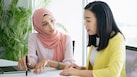 Female inspector discussing with engineer in car factory. Multi-ethnic male and female professionals are standing at car production line. They are in automotive industry.