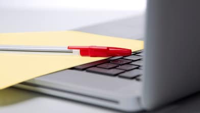 Photo of red pan on yellow piece of paper, placed on the keyboard of a laptop