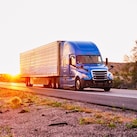 Blue truck driving down a road