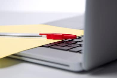 Photo of red pan on yellow piece of paper, placed on the keyboard of a laptop