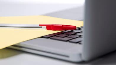 Photo of red pan on yellow piece of paper, placed on the keyboard of a laptop