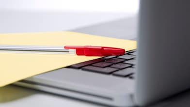 Photo of red pan on yellow piece of paper, placed on the keyboard of a laptop