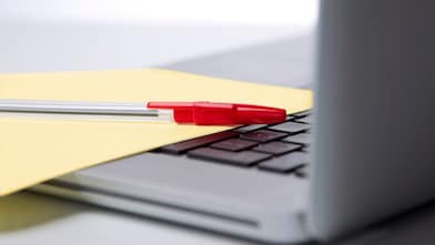Photo of red pan on yellow piece of paper, placed on the keyboard of a laptop