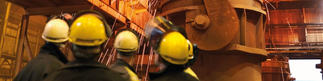 workers watching heavy machinery in a metal processing plant