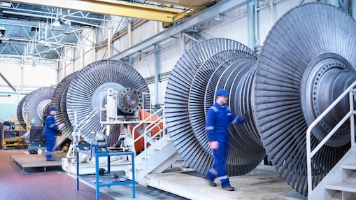 Engineers with low pressure steam turbines in repair bays in workshop