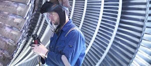Engineer repairing steam turbine blade with grinder in workshop