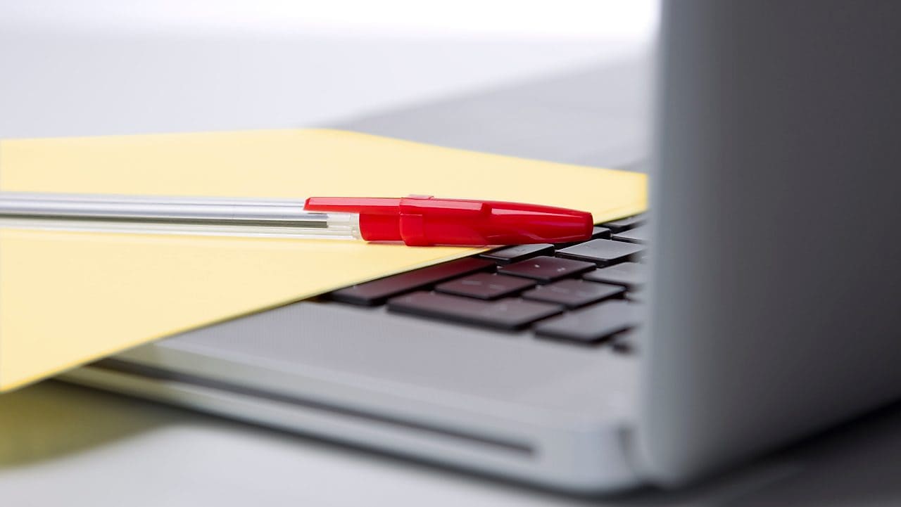 Pen and paper on a laptop