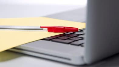 Pen and paper on a laptop