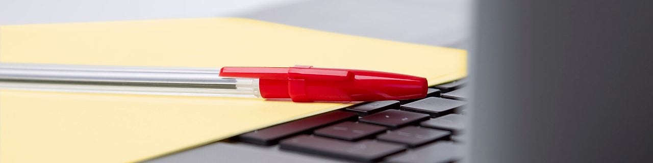 Pen and paper on a laptop