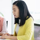 Female inspector discussing with engineer in car factory. Multi-ethnic male and female professionals are standing at car production line. They are in automotive industry.