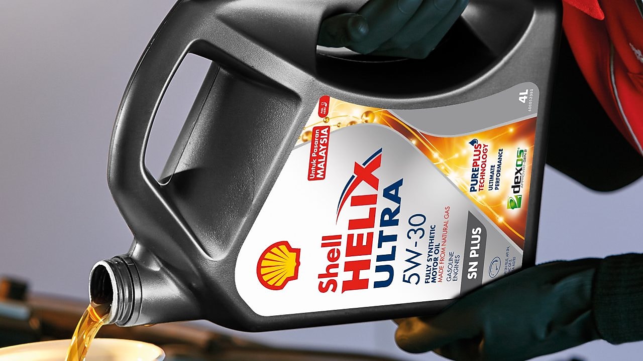 Man filling shell helix ultra oil in car