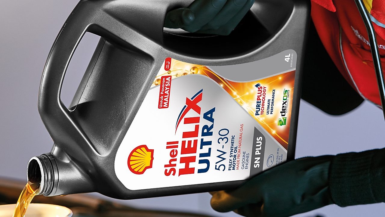 Man filling shell helix ultra oil in car
