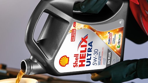 Man filling shell helix ultra oil in car
