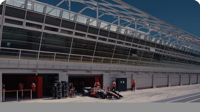 Mechanics at the Paddock of a circuit with a silver trim at the bottom of the image.