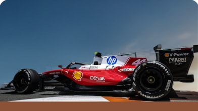 Scuderia Ferrari HP Race Car in front of a blue sky background  with a bronze trim at the bottom of the image.