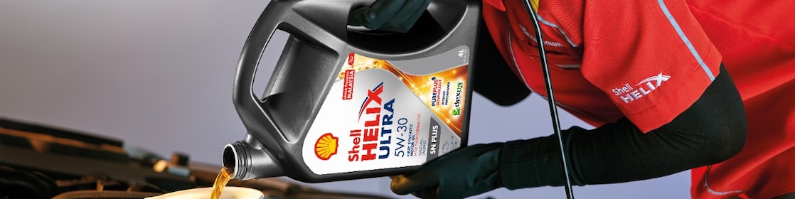 Man filling shell helix ultra oil in car