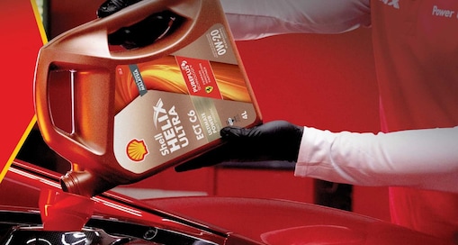 Man filling shell helix ultra oil in car