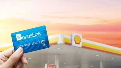 Hand holding bonuslink card with Shell station in background.