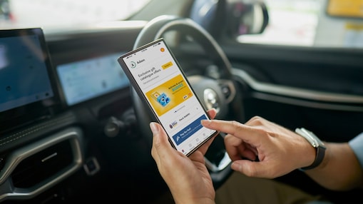 A person in a car uses a smartphone  displaying an app with promotions. The  interior is modern, suggesting a focus on  convenience and technology.