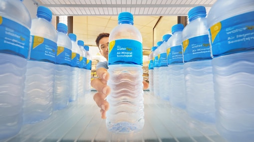 A person reaches into a refrigerator full of  Shell Select water2go bottles, selecting one.  The bottles indicate it is the Shell Select  water2go. The setting feels cool and  refreshing.